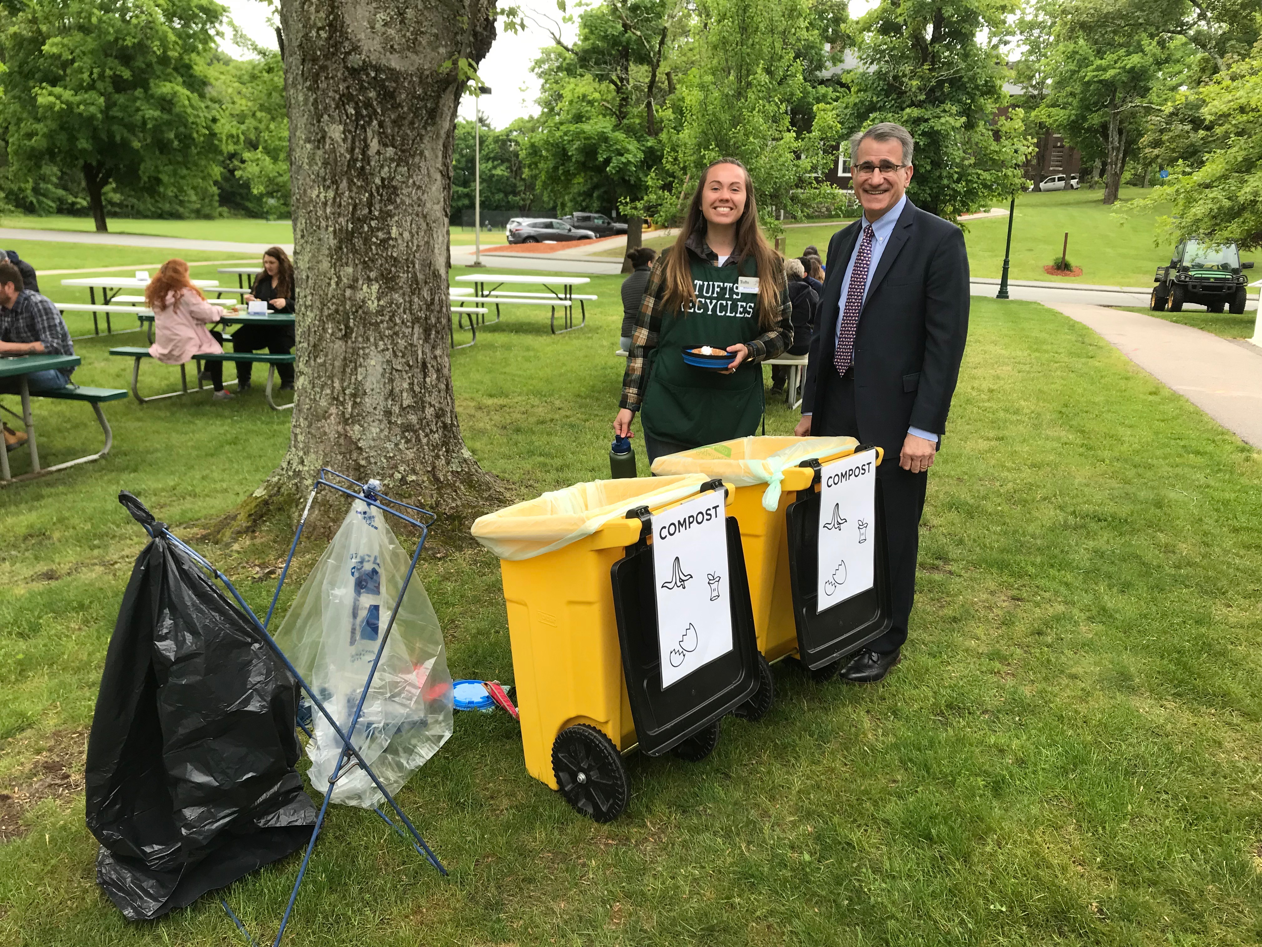 A woman and a man in smiling near compost bins at a zero waste event