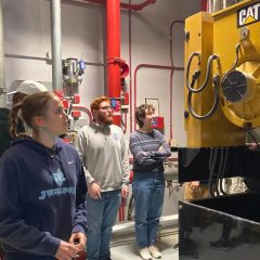 Students look at a large yellow engine