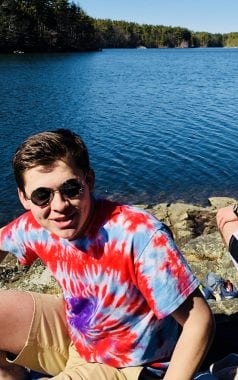 Picture of Mike, an eco-rep, by a body of water in a tie dye shirt and sunglasses