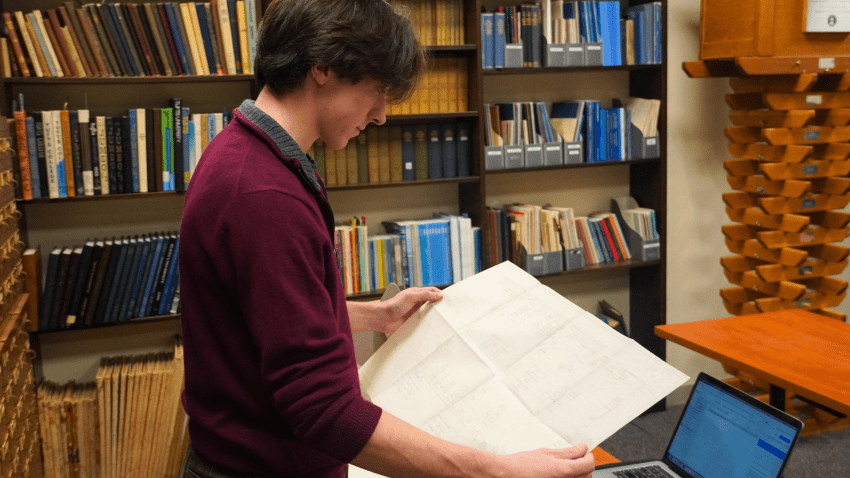 Rhys examines an archival blueprint in the Tufts Archival Research Center