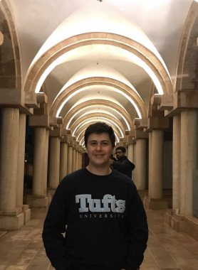 Boy in Tufts University Sweater standing in the center of a corridor